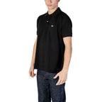Man wearing black short-sleeve polo shirt with collar and blue jeans, white background