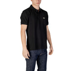 Man wearing black short-sleeve polo shirt and dark blue jeans on white background