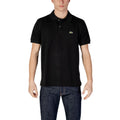 Man wearing a black polo shirt with short sleeves and blue jeans on white background