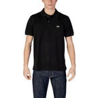 Man wearing a black polo shirt with short sleeves and blue jeans on white background